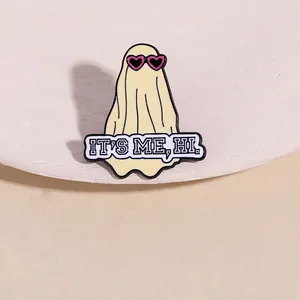 Detail shot of cartoon ghost enamel pin with heart sunglasses and It's Me, Hi slogan