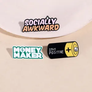 Macro shot of Socially Awkward and Money Maker enamel pins on a neutral background