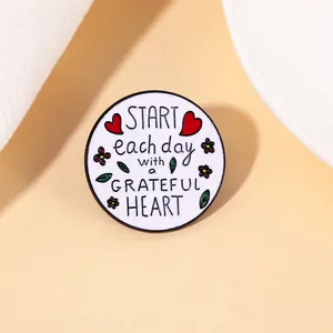 Détail du pin's émaillé avec message motivant et motifs de fleurs rouges élégantes