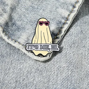 Ghost enamel pin with pink heart glasses and 'IT'S ME, HI' text on denim jacket
