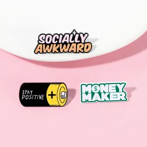 Detailed close-up of three enamel pins: Socially Awkward, Stay Positive, and Money Maker