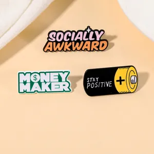 Detailed close-up of three enamel pins with Socially Awkward and Money Maker motifs