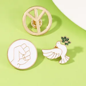 Detailed view of white enamel peace dove, fist, and peace sign pins with gold plating