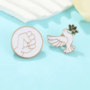 Detail of peace dove and fist with chain enamel brooch pins on blue background
