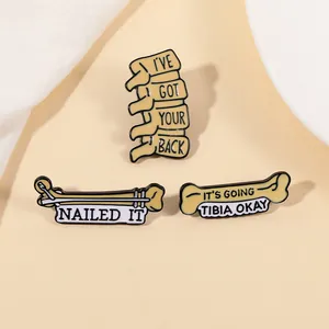 Détail de pins en émail médical montrant la colonne vertébrale et l'os sur tissu beige
