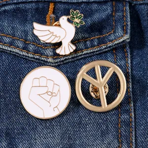 Detail of 3-piece peace dove enamel pins set pinned on deep blue denim fabric background