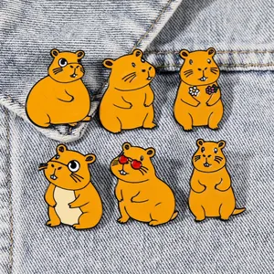 Detail view of colorful enamel capybara badges pinned on light blue denim fabric texture