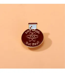 Detalle del pin esmaltado de matraz químico con símbolo atómico y grabado dorado