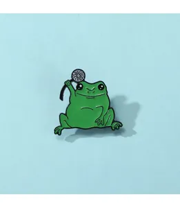 Gros plan détaillé d'une mignonne broche grenouille émaillée verte avec accessoire noir
