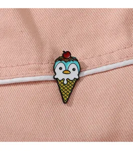 Nahaufnahme einer süßen Pinguin-Eiscreme-Emaille-Nadel auf rosa Stoffhintergrund