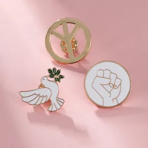 Detailed close-up of peace dove enamel pins with olive branch and geometric symbols