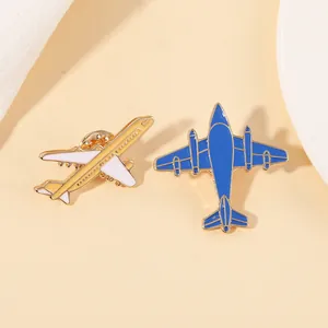 Détail de deux mini broches avion en émail blanc et bleu avec finition dorée