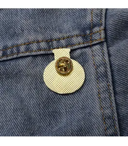 Detalle de la parte trasera dorada de la insignia con cierre de mariposa en denim