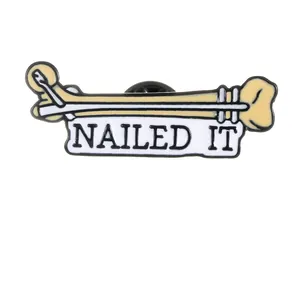 Broche médicale émaillée avec os, clou chirurgical et texte Nailed It humoristique
