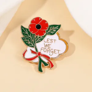 Détail macro du pin's émaillé en forme de coquelicot rouge avec texte Lest We Forget