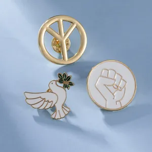 Close-up of enamel peace dove brooches with olive branch and gold symbols