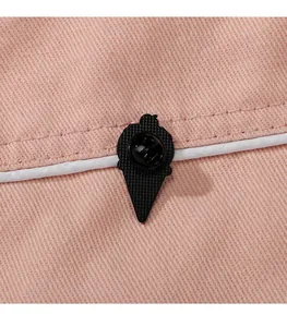 Detailansicht der schwarzen Pin-Rückseite mit Gummiverschluss auf rosa Stoffgrund