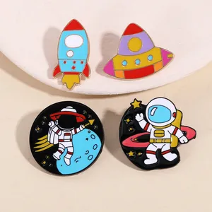 Detail of four creative astronaut and UFO enamel pins with vibrant colors and gold metal edges