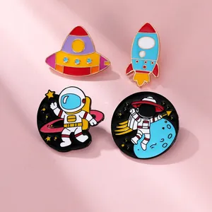 Detailed view of 4-piece astronaut and spaceship enamel pins on pink background