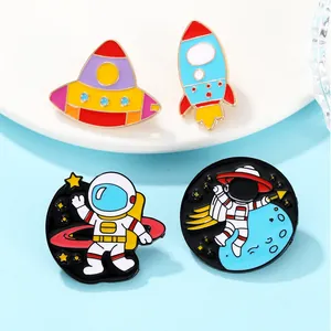 Close-up of four colorful space enamel pins including astronauts and a rocket on blue