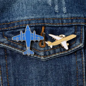 Détail de pin's émaillés en forme d'avion à hélice bleu et de jet moderne sur du denim