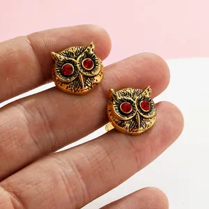 Detailed close-up of antique gold owl cufflinks with vibrant red rhinestone eyes