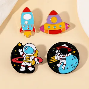 Detail of four colorful astronaut enamel pins featuring rocket, UFO, and space themes