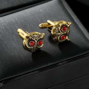 Macro view of vintage gold owl cufflinks with red crystal eyes on black texture