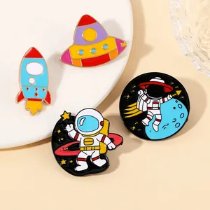 Detailed view of 4 cute astronaut enamel pins with UFO and rocket on a beige background