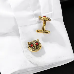 Golden owl cufflinks with red rhinestone eyes on a white formal shirt cuff