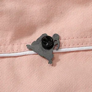 Broche en émail noir avec fermoir papillon sur fond de tissu rose délicat