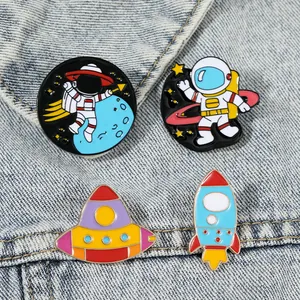 Set of four cute space themed enamel astronaut and UFO pins on blue denim fabric