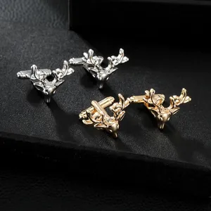 Macro shot of gold and silver deer head cufflinks on a black leather textured background