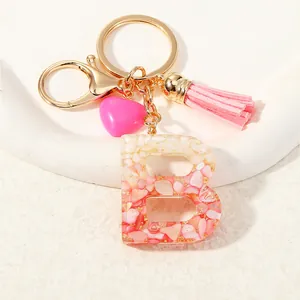 Resin letter B keychain with pink leather tassel and gold foil flakes on white plate