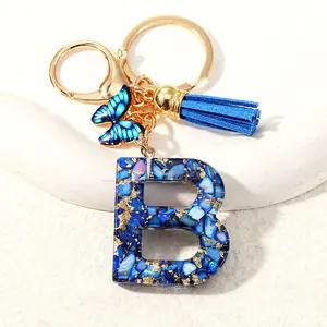 Letter B initial keychain with blue resin, gold foil, butterfly, and tassel charm