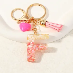 Detail of resin letter F keychain with pink gold foil, tassel and heart charm