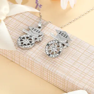 Detail of 2025 graduation cap and compass necklace with rhinestones on a silk gift box