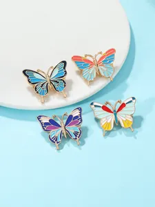 Vue détaillée de quatre broches papillon en émail coloré avec cadre en métal doré