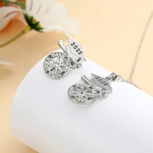 Close-up of 2025 graduation necklace and earring set with compass and mortarboard detail