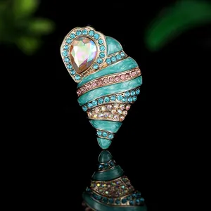 Macro detail of enamel sea shell brooch with colorful rhinestones on gold base