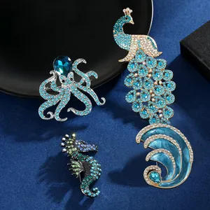Macro detail of rhinestone octopus and peacock brooches with blue crystals and enamel