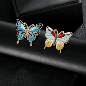 Détails de deux broches papillon colorées en émail avec des motifs d'ailes et dorure or