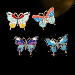 Détail de quatre broches papillon en émail coloré sur un fond noir avec des reflets