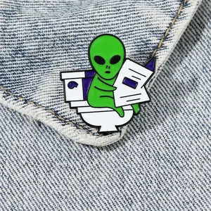Insigne d'extraterrestre vert drôle lisant le journal sur les toilettes pour vêtements