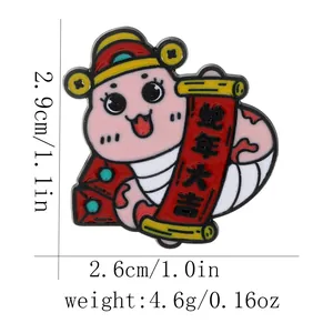 Detail of pink cartoon snake enamel pin with New Year scroll and dimensions 2.9cm x 2.6cm