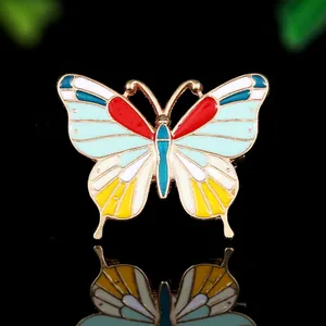 Gros plan détaillé d'une épingle émaillée papillon colorée avec dorure sur fond noir