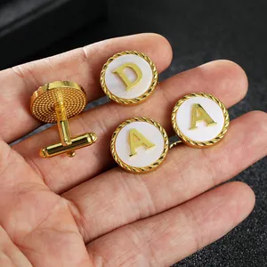 Close-up of gold-plated alphabet cufflinks with white mother-of-pearl inlay and twist edge