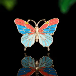 Détail macro d'une épinglette papillon en émail coloré avec des contours dorés brillants