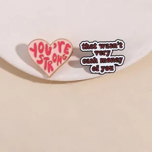 Detailed shot of enamel brooches with You Are Strong and That Wasn't Very Cash Money text