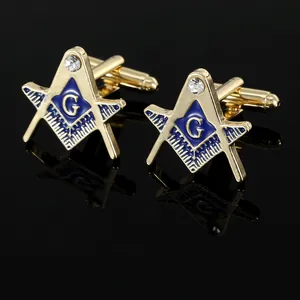 Detail van gouden vrijmetselaars manchetknopen met blauw emaille G-logo en kristal